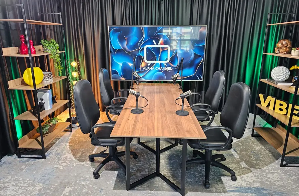 Cenário de podcast do estúdio da Produtora 76, com mesa, quatro cadeiras e microfones